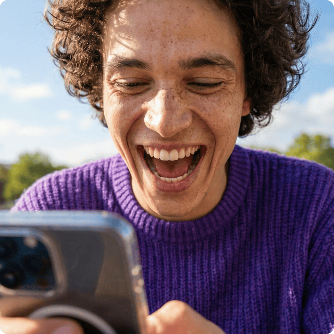 Quatres personnes souriantes devant leur téléphone mobile